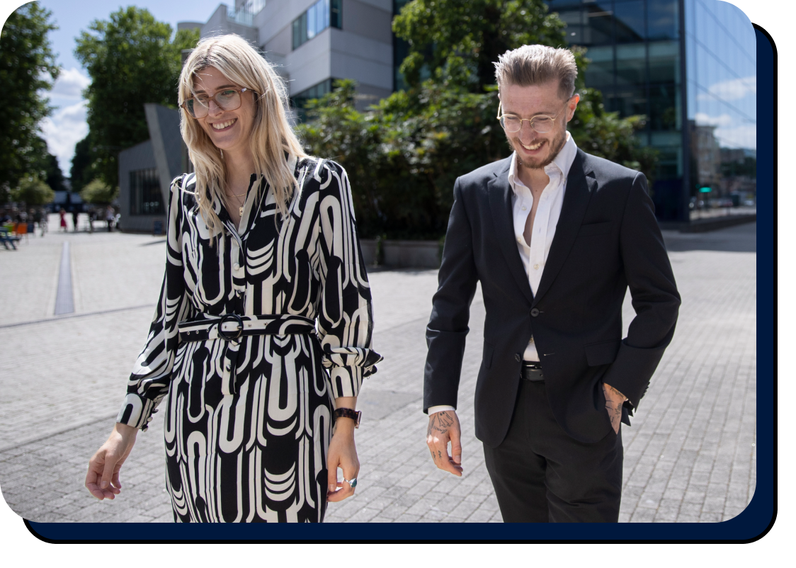 Professional man in suit and woman in printed dress walking in the city