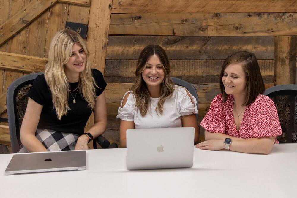 Three female colleagues looking at a laptop