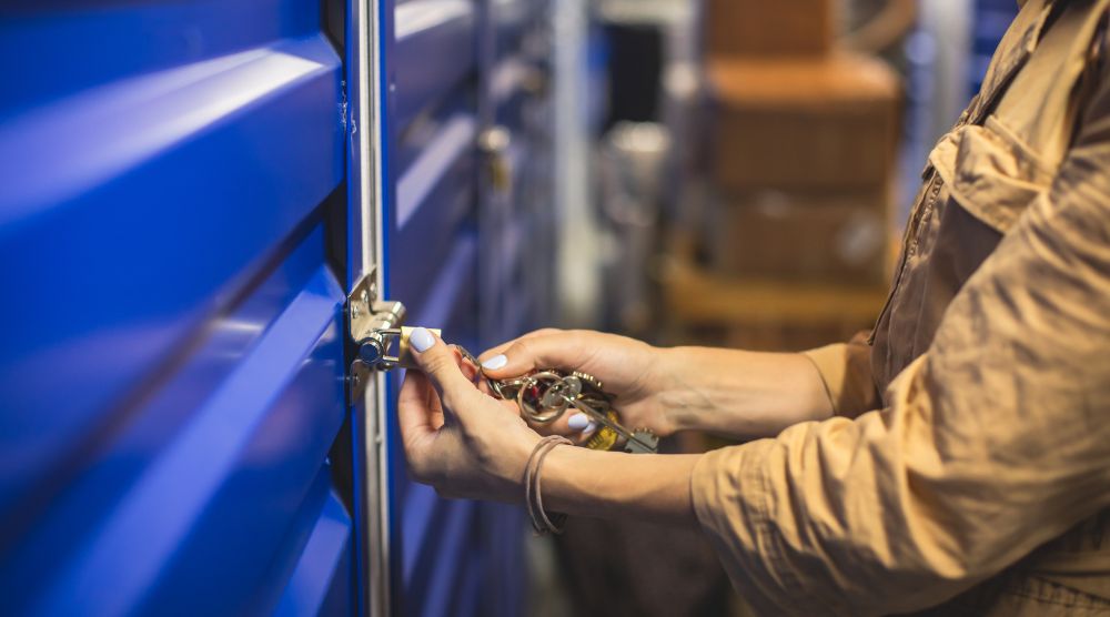 A woman locking a blue storage unit with a padlock